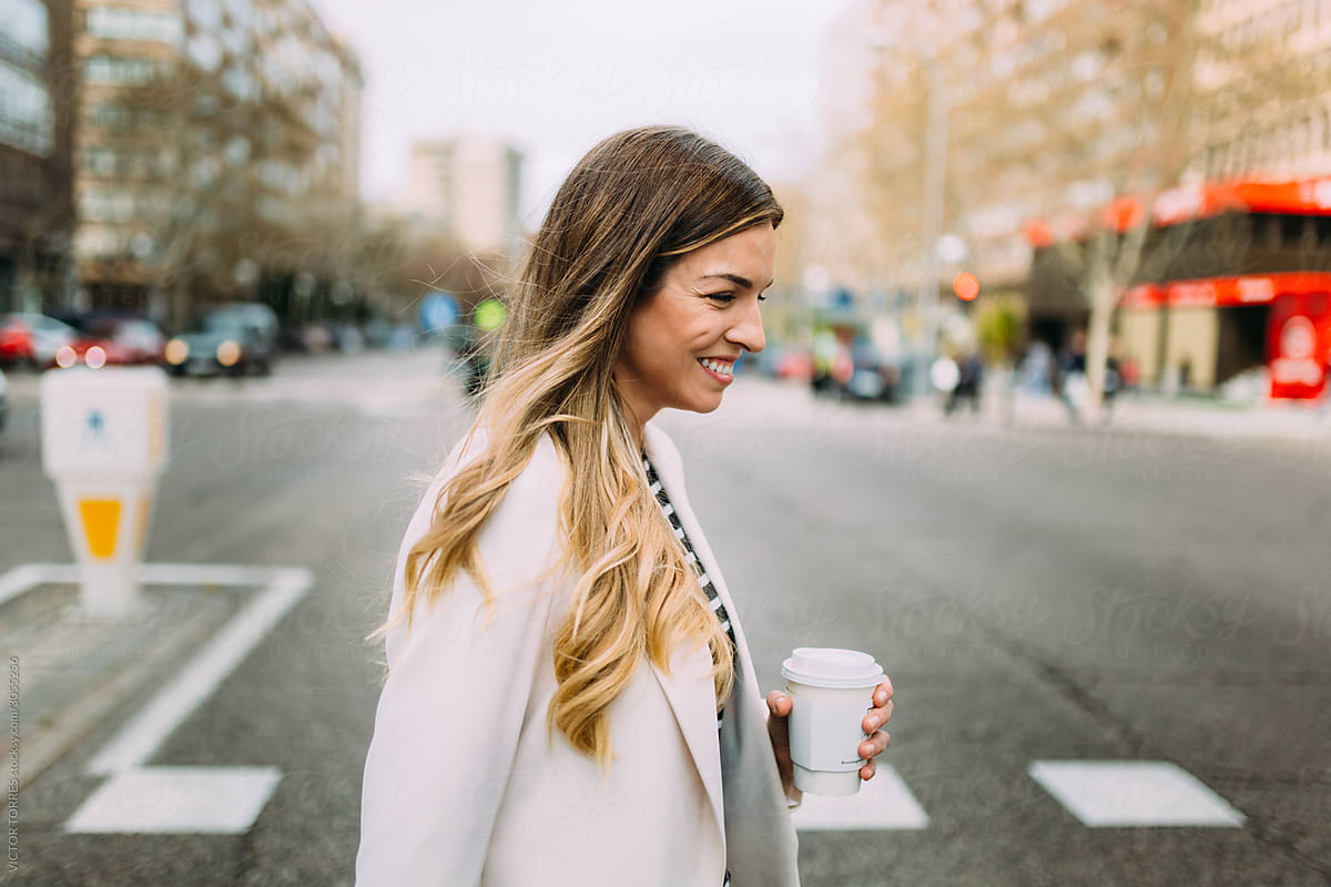 Young businesswoman crossing the street holding a coffee mug