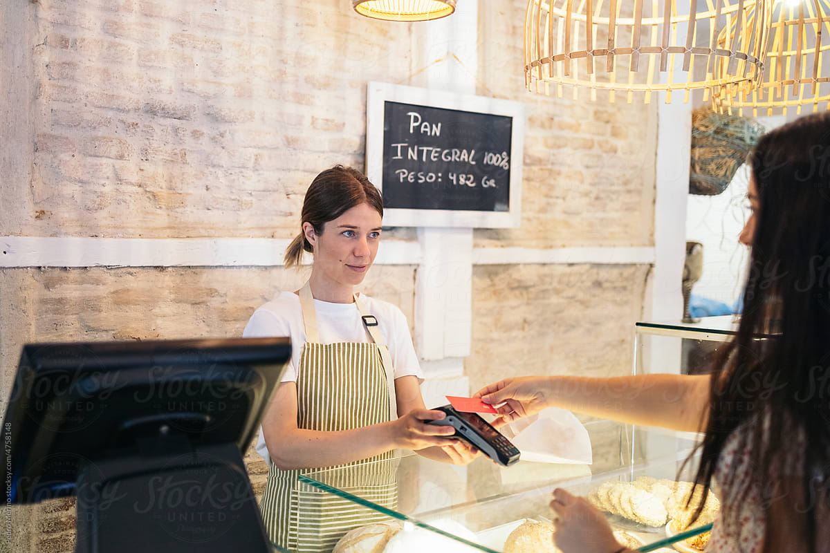 Worker of a pastry shop charging a client with the dataphone