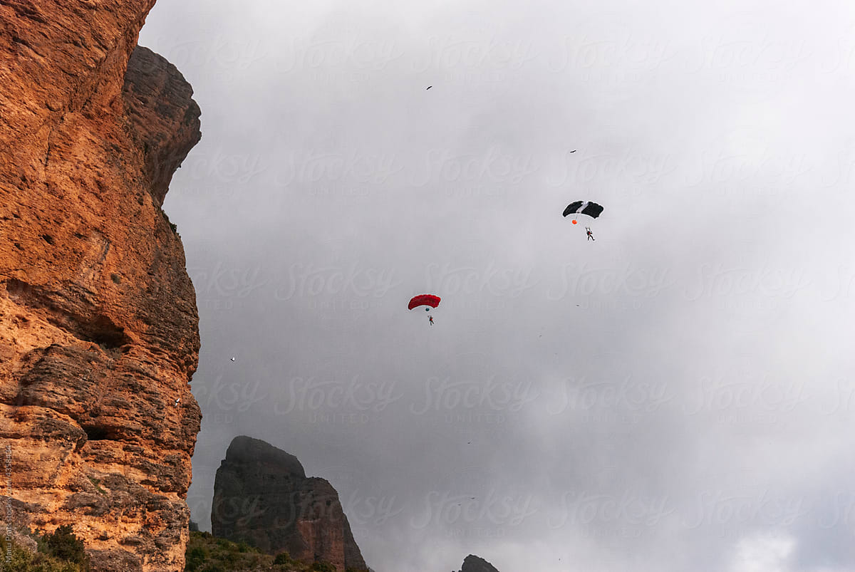 Anonimous base jumpers flying over mountain range