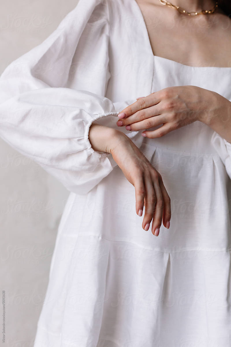 Woman hands closeup in white dress touching and adjusting her sleeve