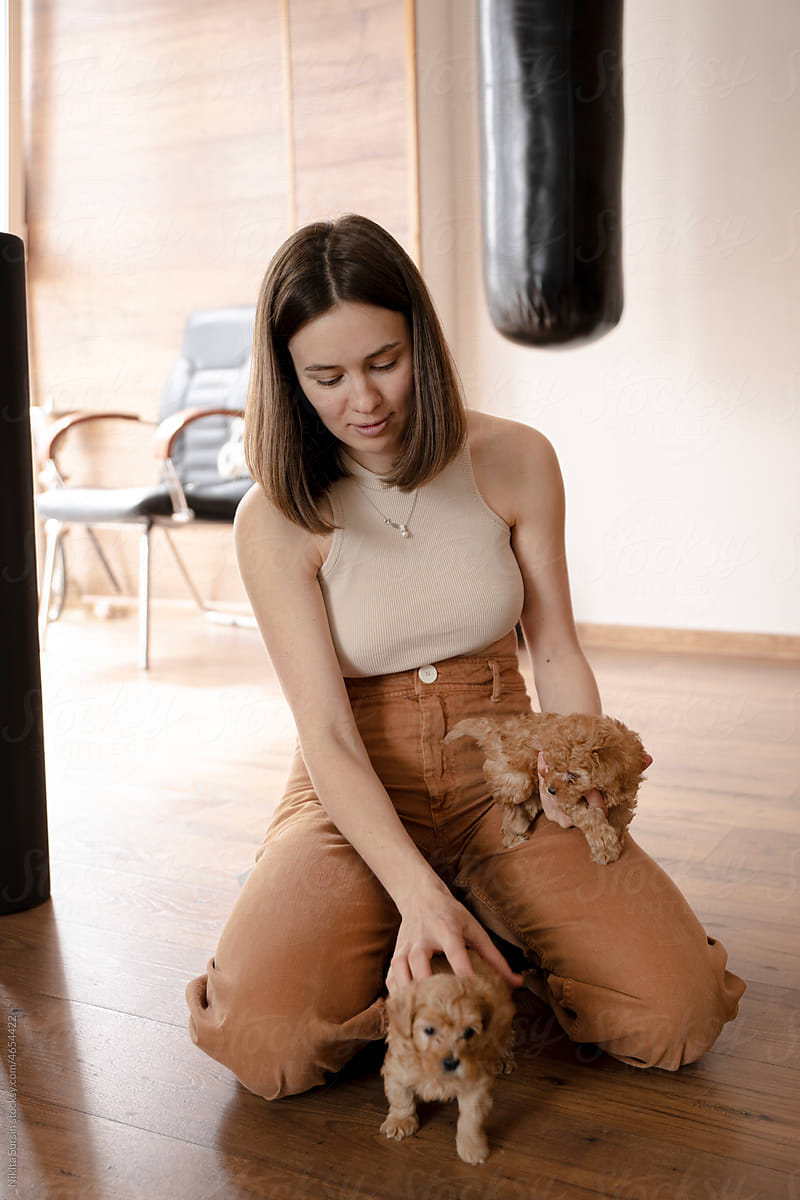 young woman playing with her dogs in apartment