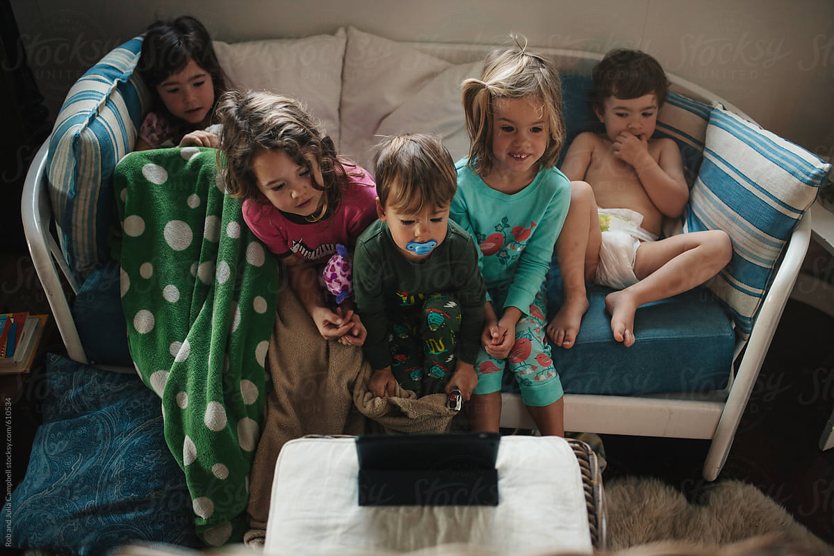 Group of young kids watching cartoons on tablet in pajamas