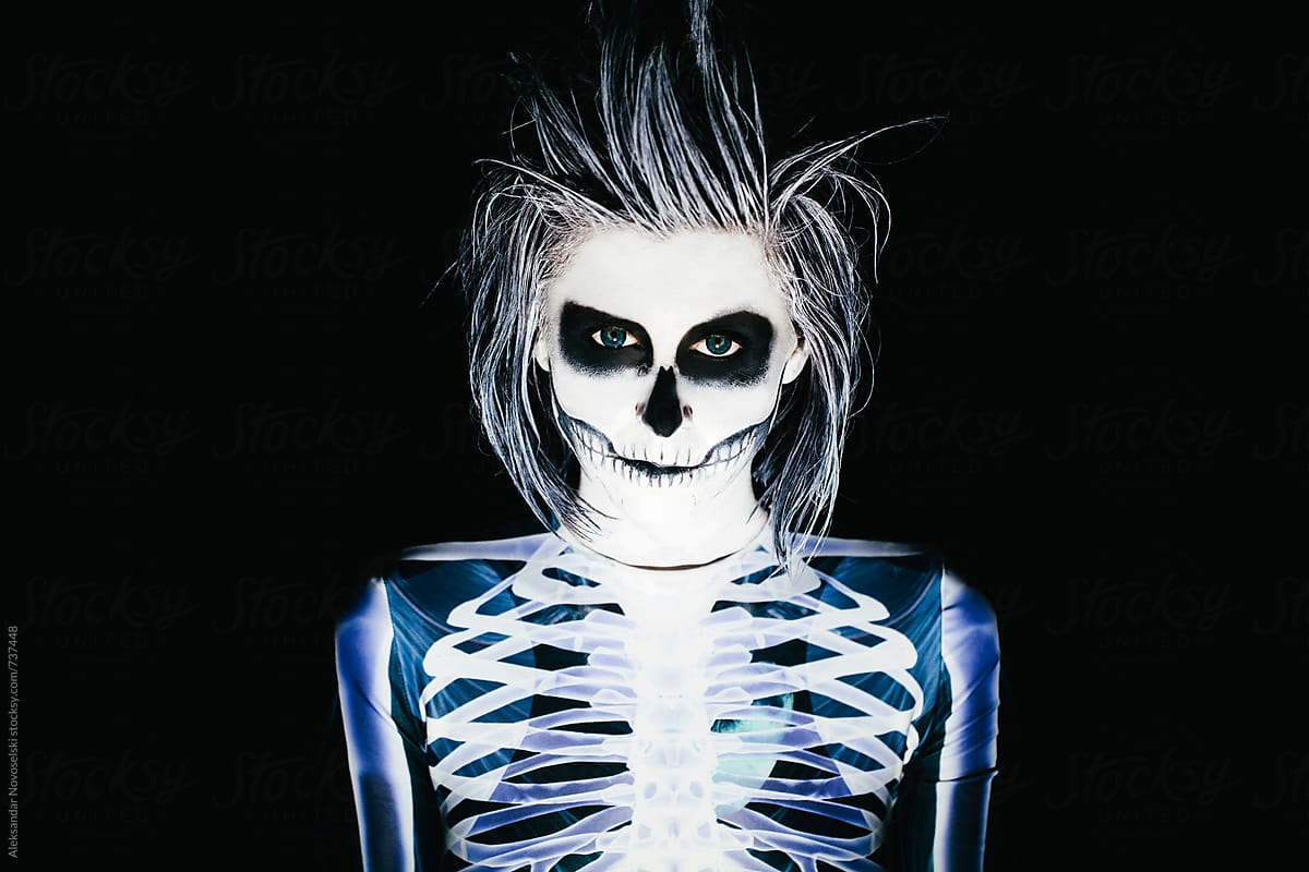 Spooky portrait of woman in skeleton costume and halloween make up on black background