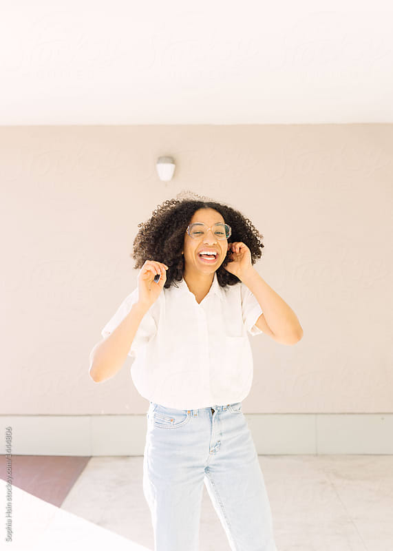 Portrait of girl with great hair laughing in pastel background