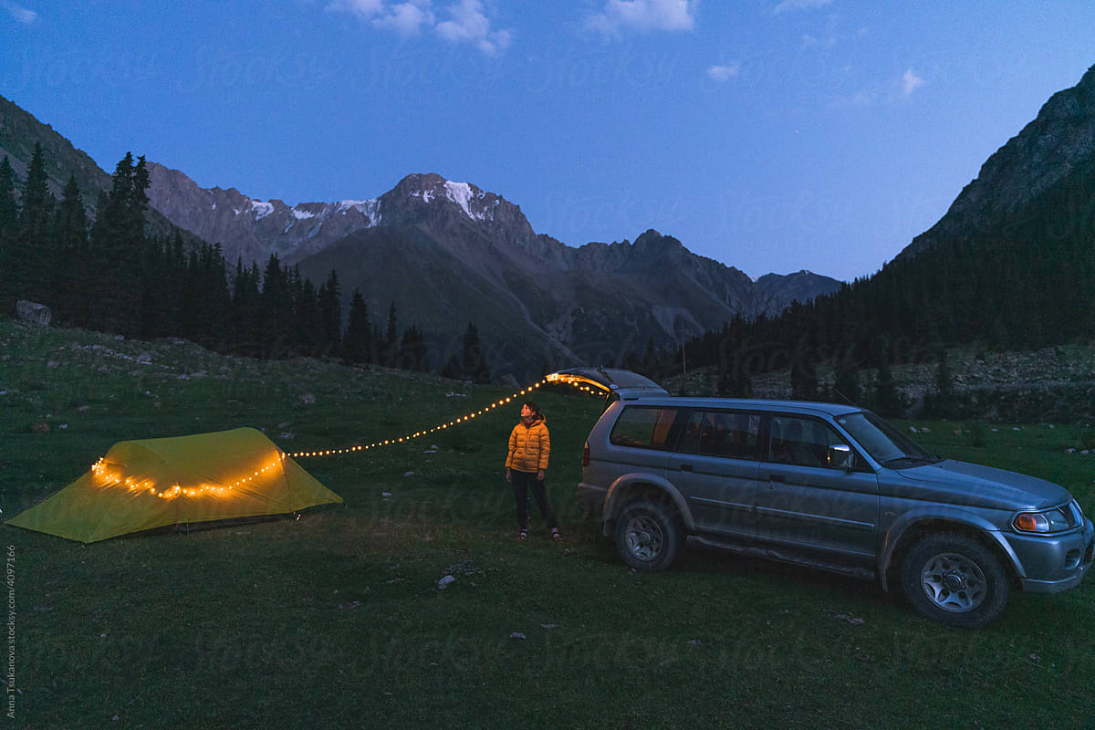 Woman near the car and tent in mountains