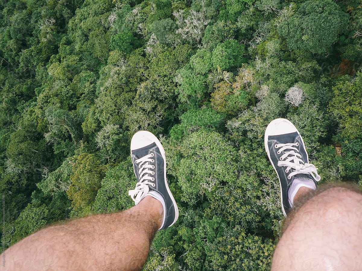 Dangling feet pov view of paragliding adventure over forest