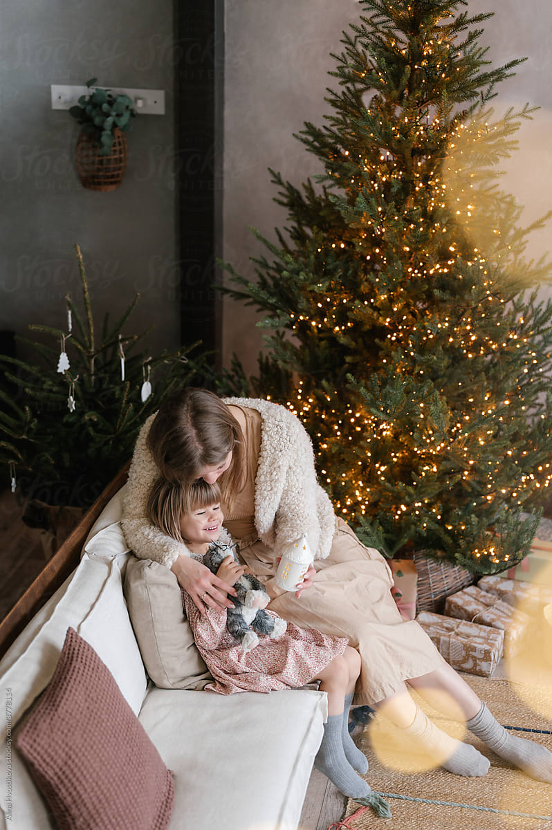 Loving mother with girl on couch at Christmas tree