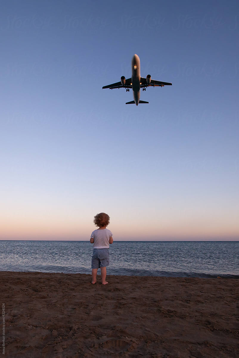 wanderlust travel, child watching airplane in sky