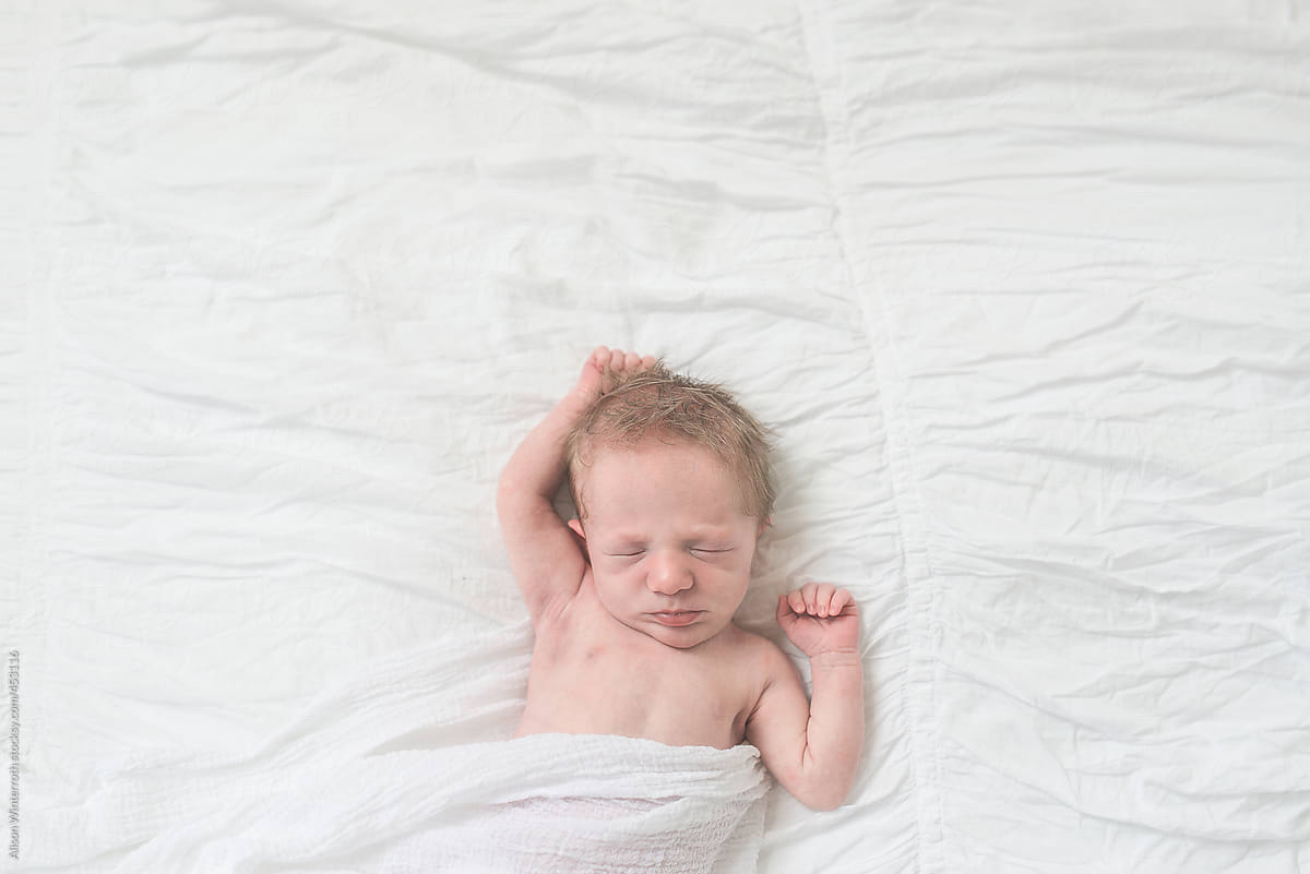 A Newborn Baby Boy Sleeping On A White Bed