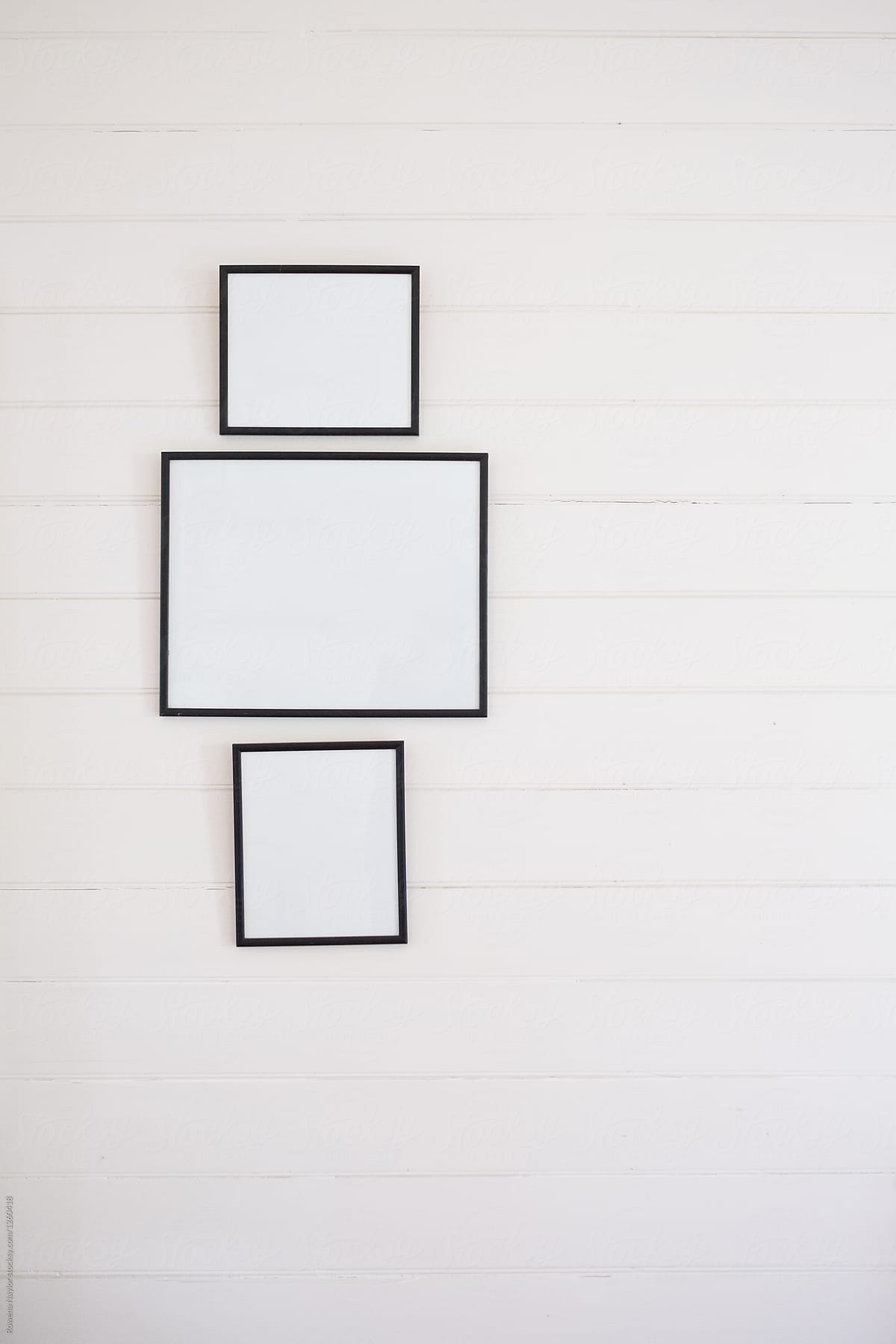 Trio of empty frames hung on weeatherboard cottage wall