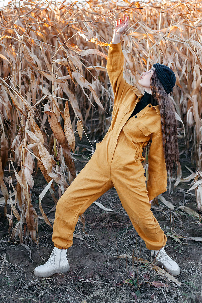 Woman in stylish clothes standing in corn field
