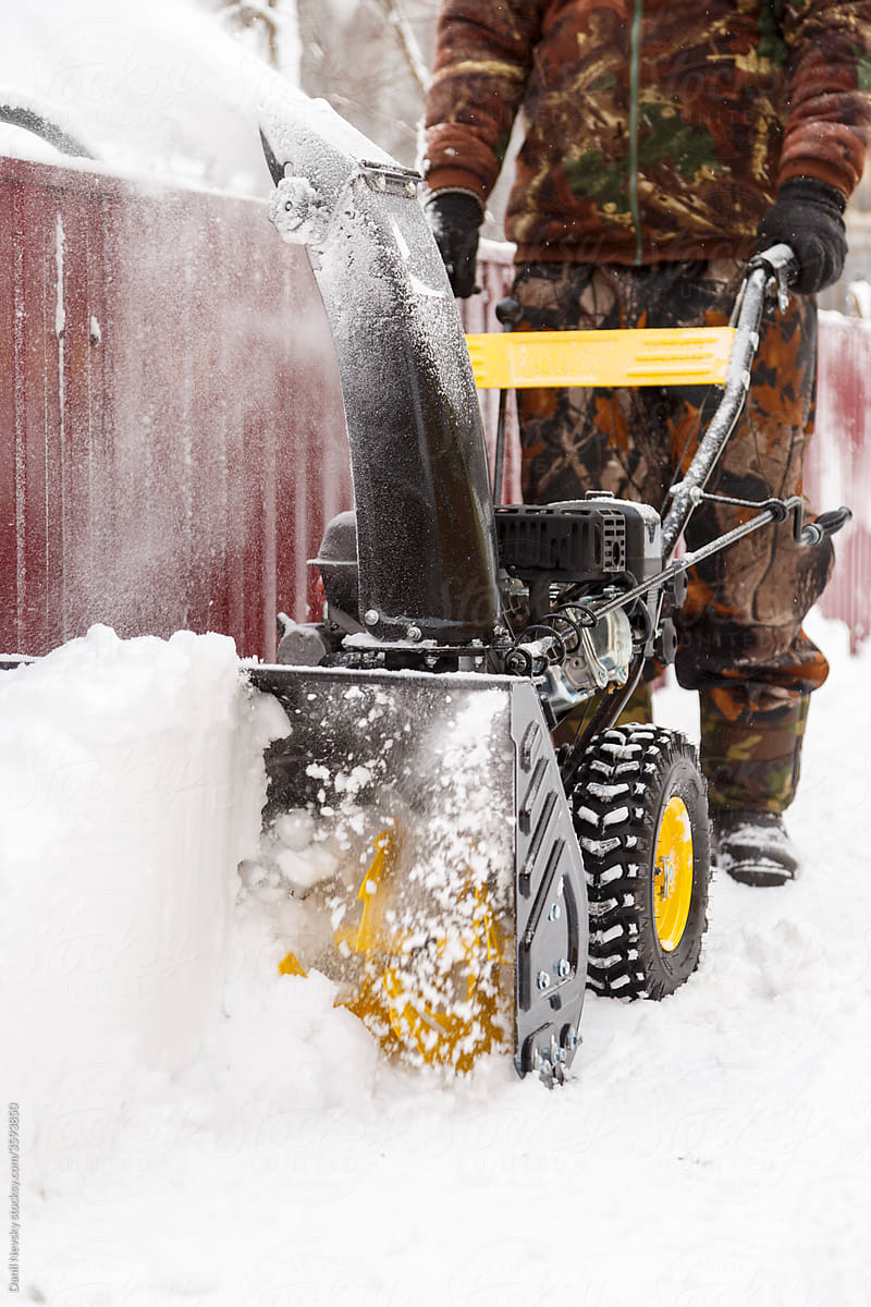 Crop man in camouflage removing snow from yard