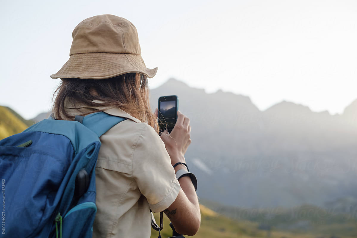 Woman hikes in the mountain area making photo with smartphone