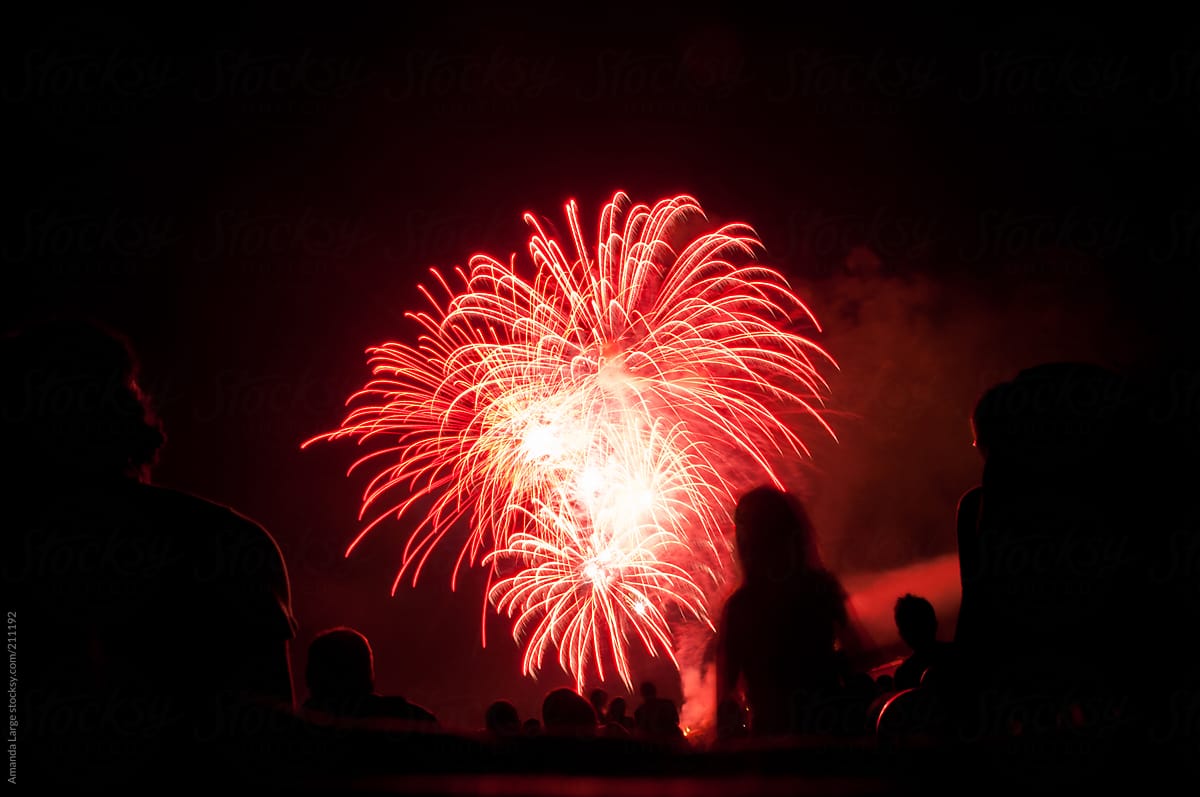 red fireworks with silhouettes of spectators  in foreground