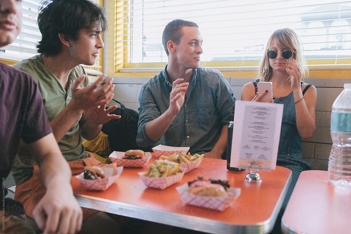 Young Group of Friends Having Fun Eating Beach Food and Using Smartphone Technology in Diner