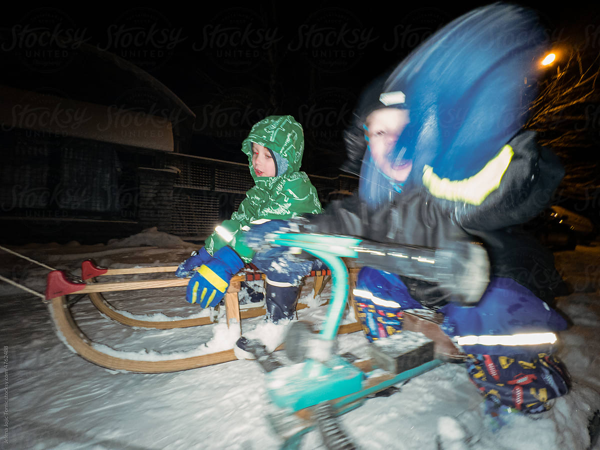 Siblings on sleds riding fast on their sleds