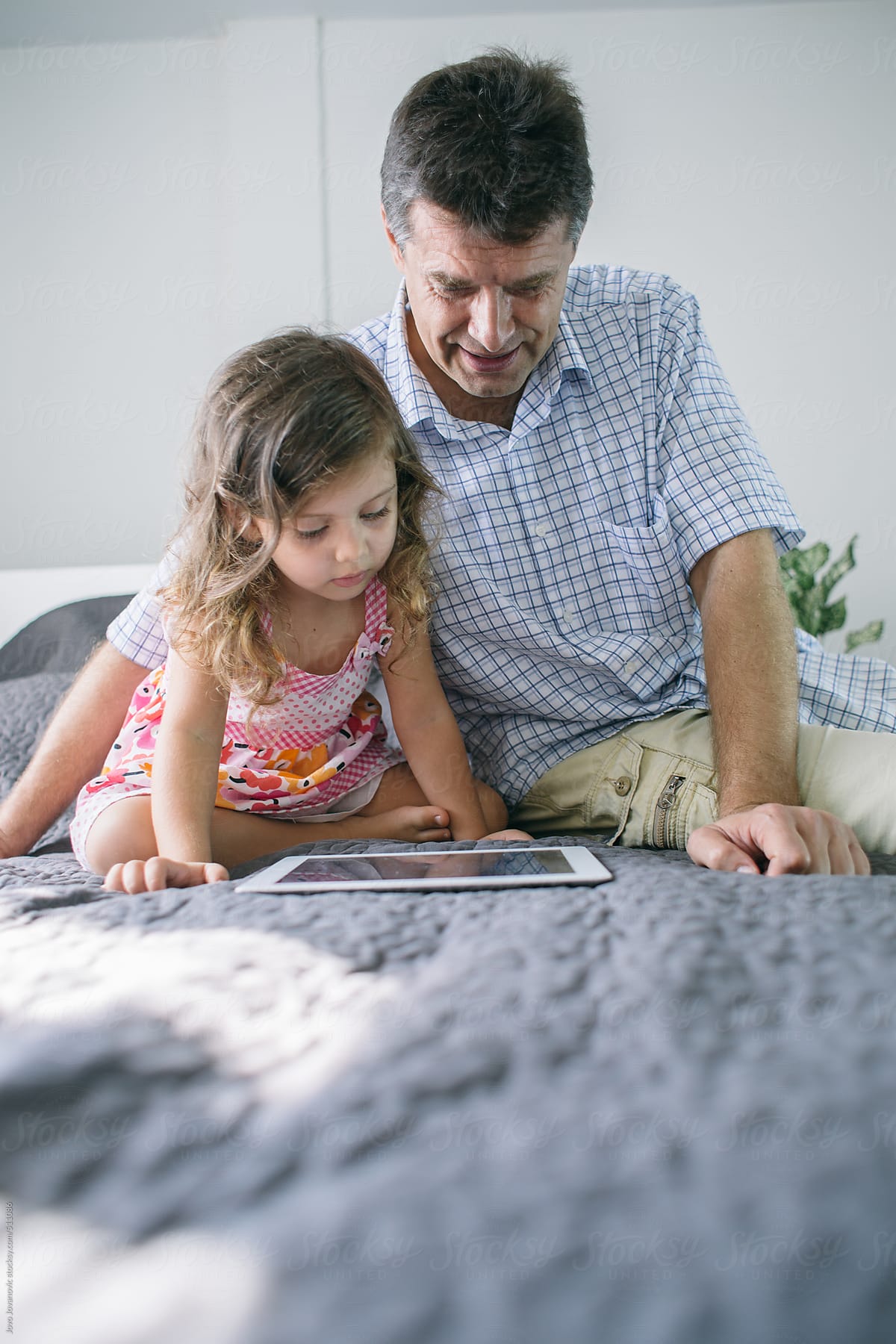 Father and his daughter watching cartoons on tablet