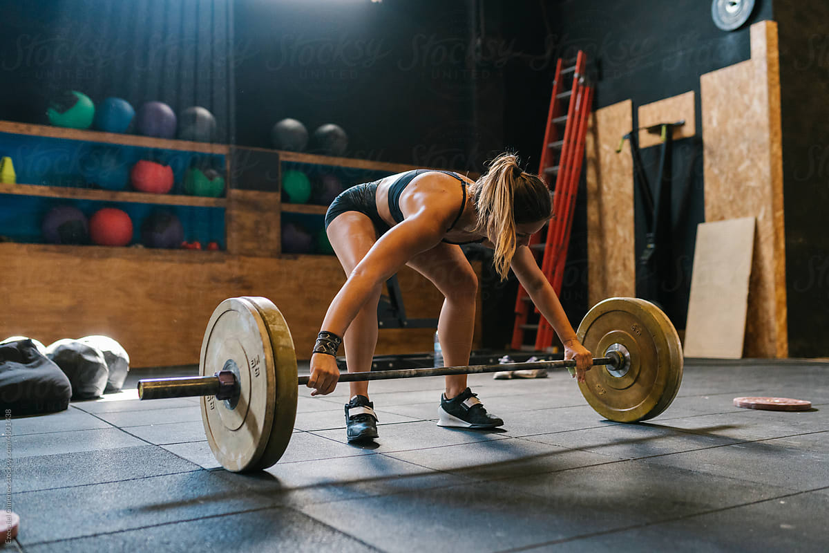 Fit sportswoman prepares to lift heavy barbell
