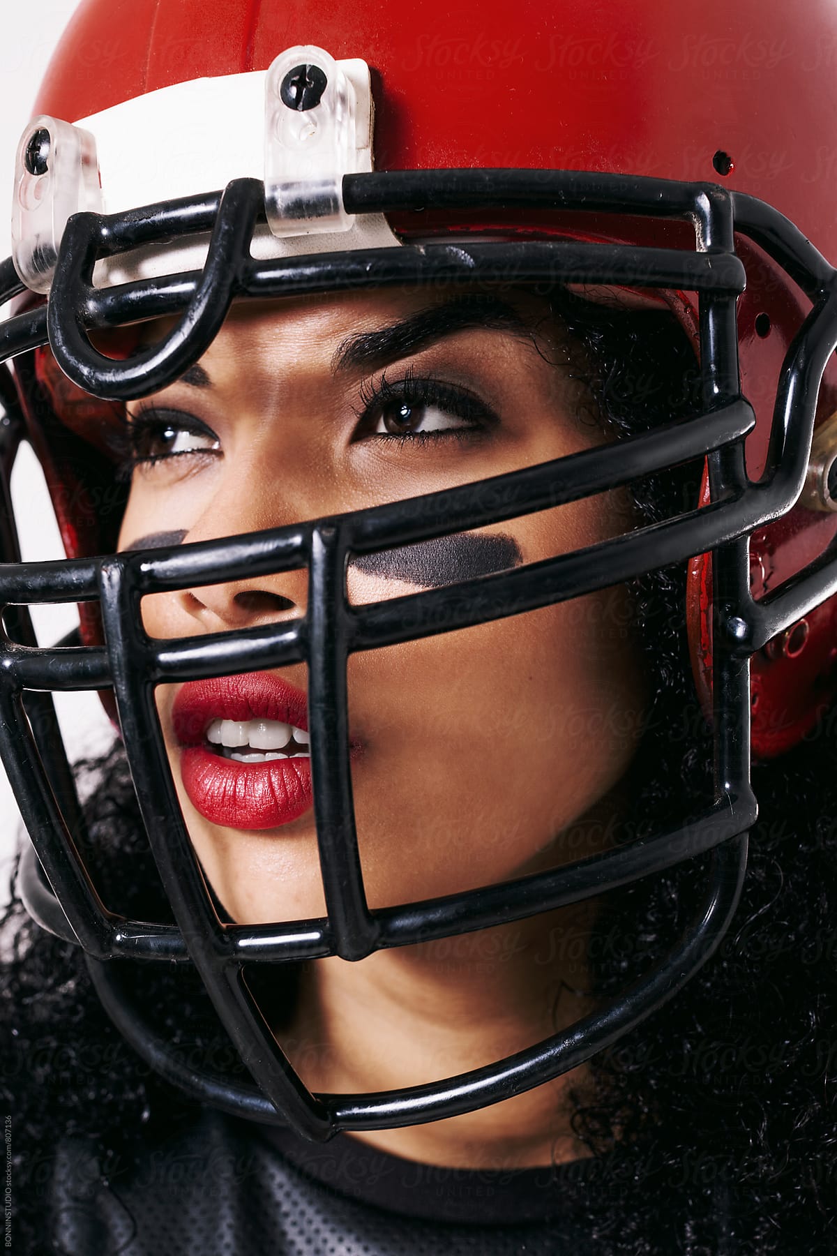 Portrait of a woman wearing a red football helmet.