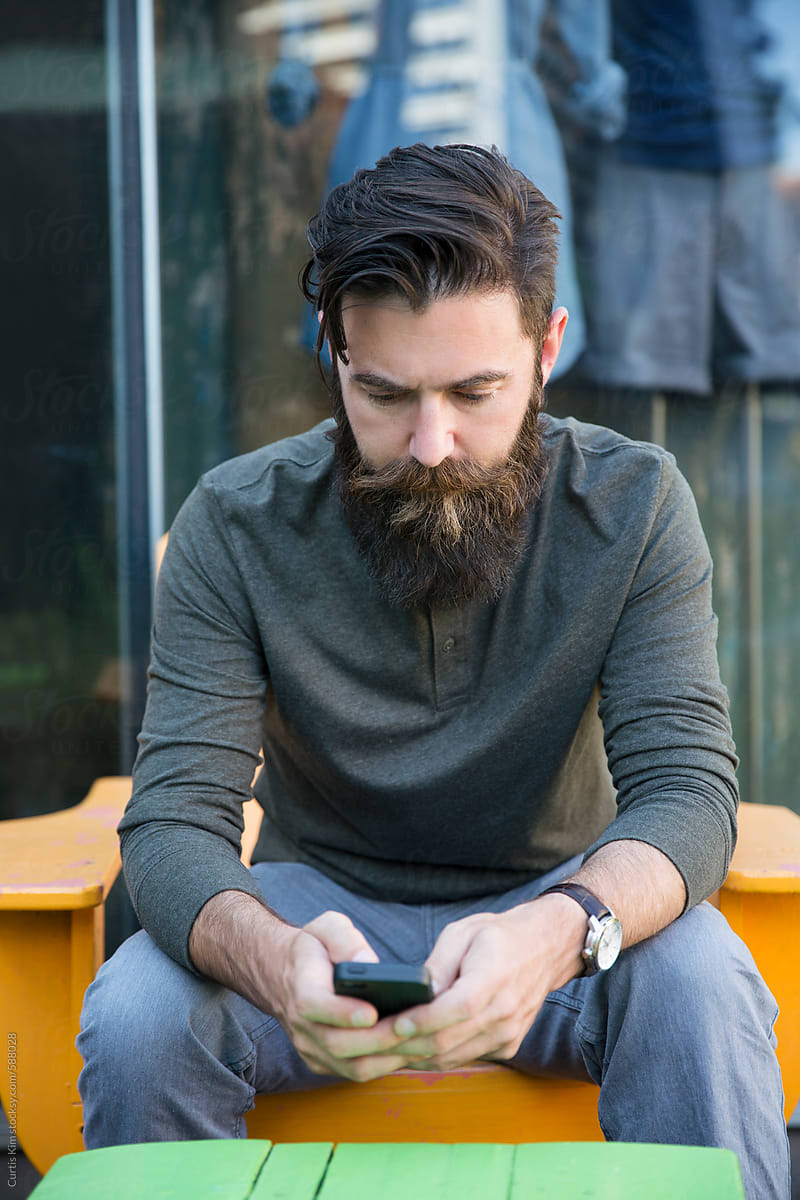Bearded man holding mobile phone