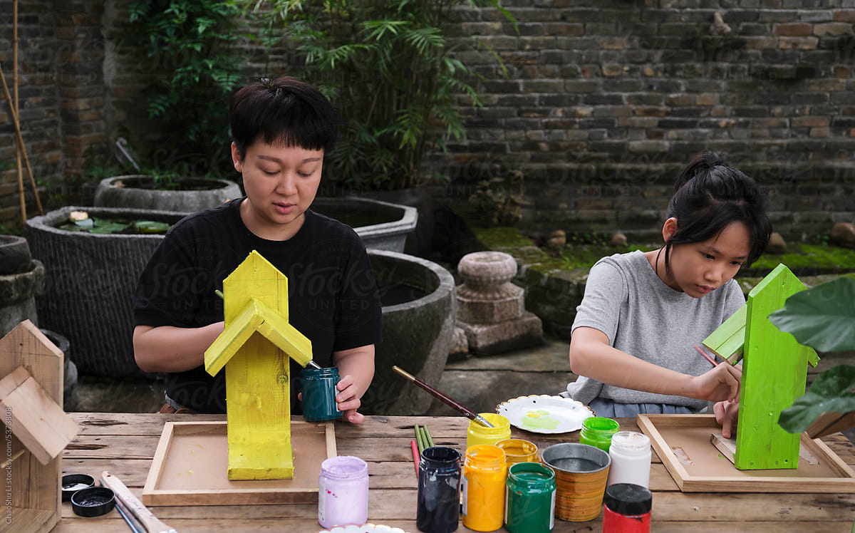 Asian mother and daughter coloring bird feeder painting