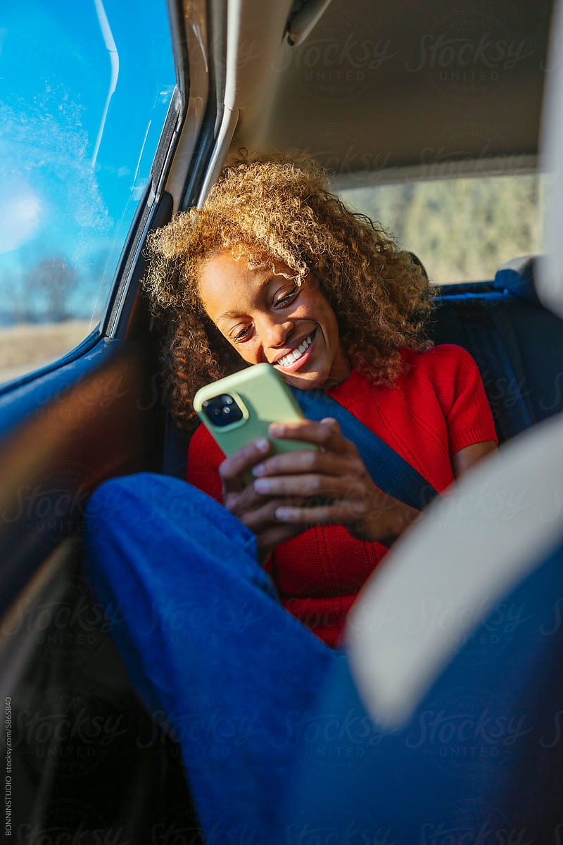 Smiling woman looking at phone in car