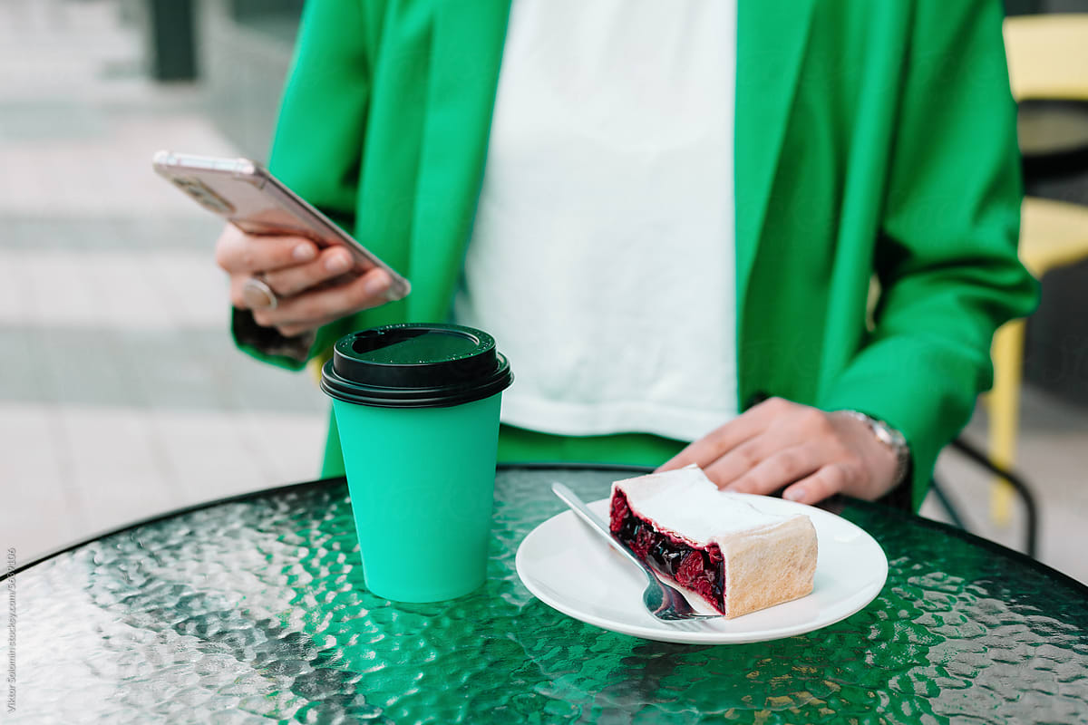 Crop woman with takeaway coffee, cherry pie and smartphone