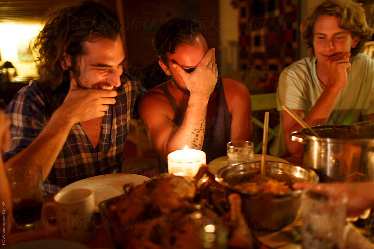 Friends sit around laughing and enjoying a dinner in candlelight