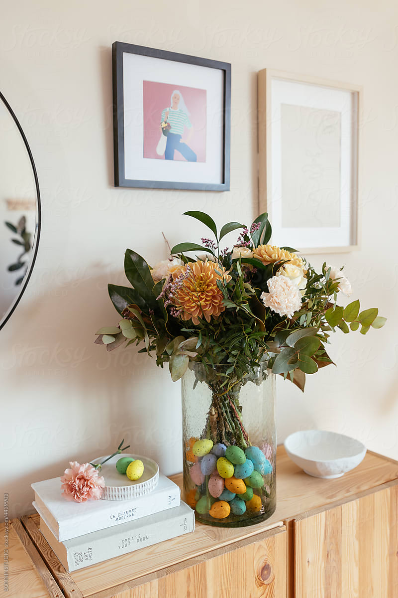 Bunch of flowers with eggs in vase on table