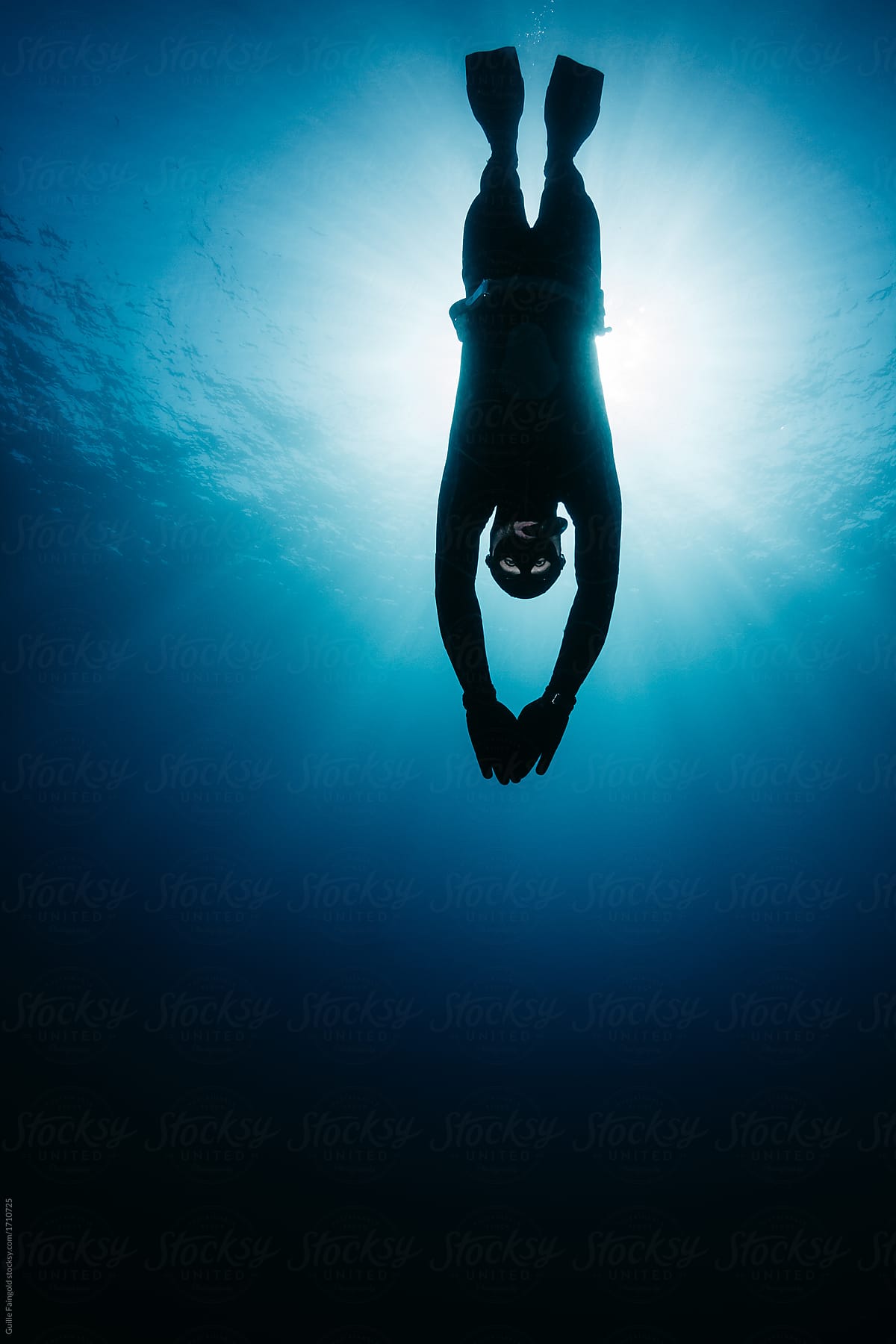 Silhouette of man freediving in ocean