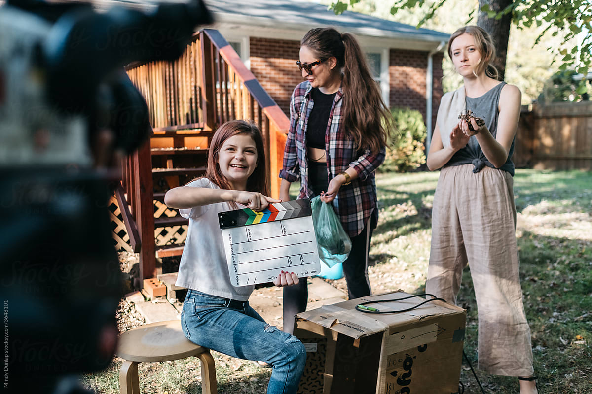 Young girl holding clapboard in front of video camera