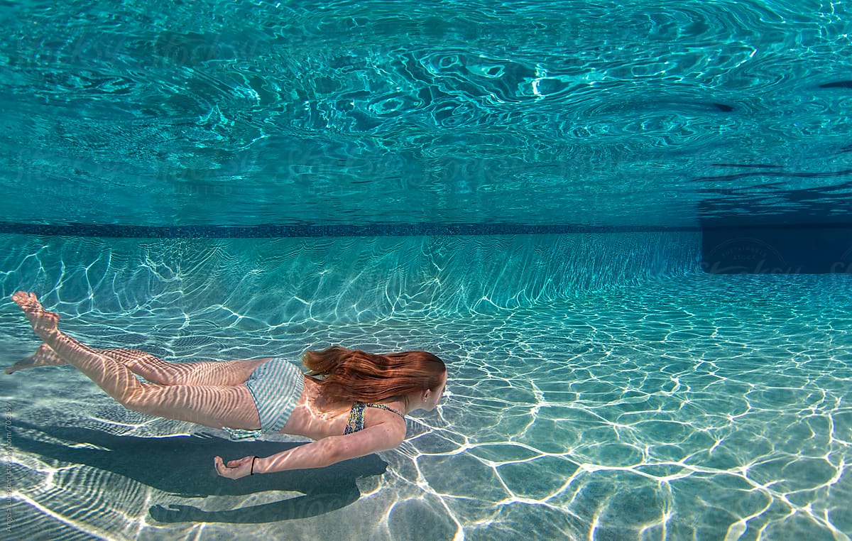 Teenage girl swimming along the bottom of a large swimming pool