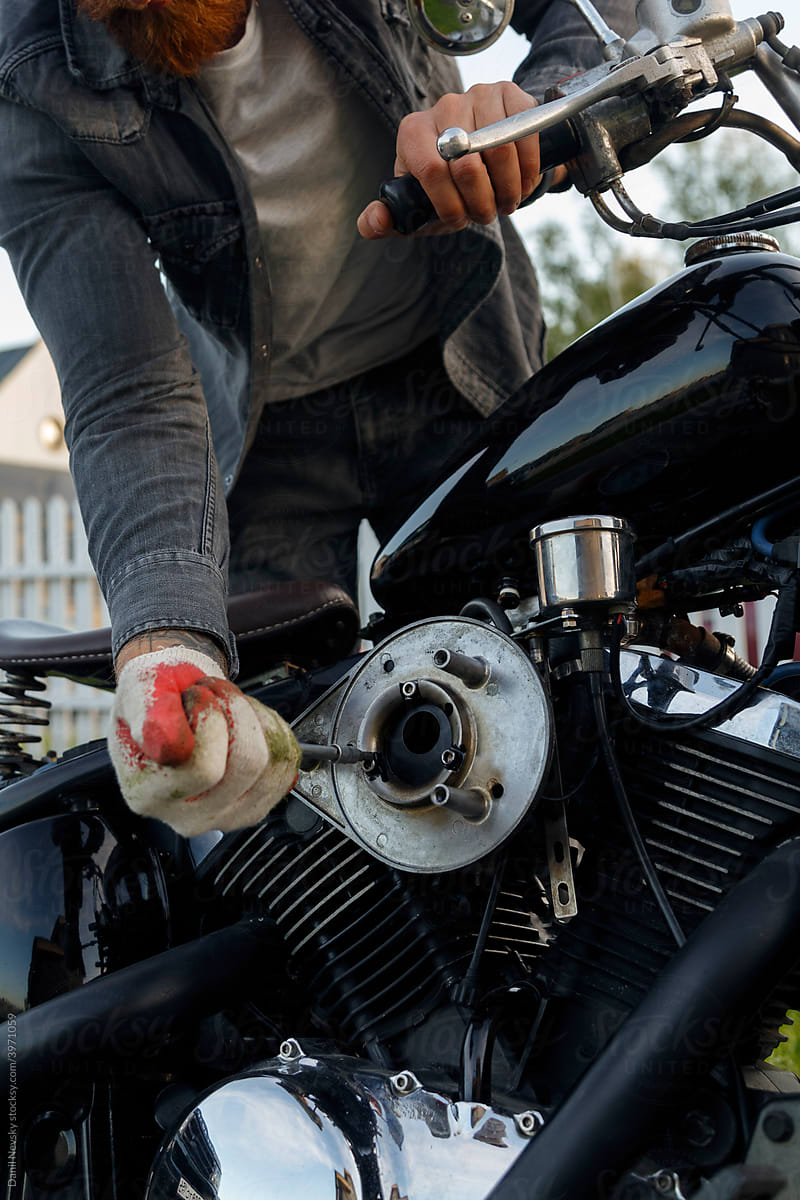 Crop male mechanic repairing engine of motorbike