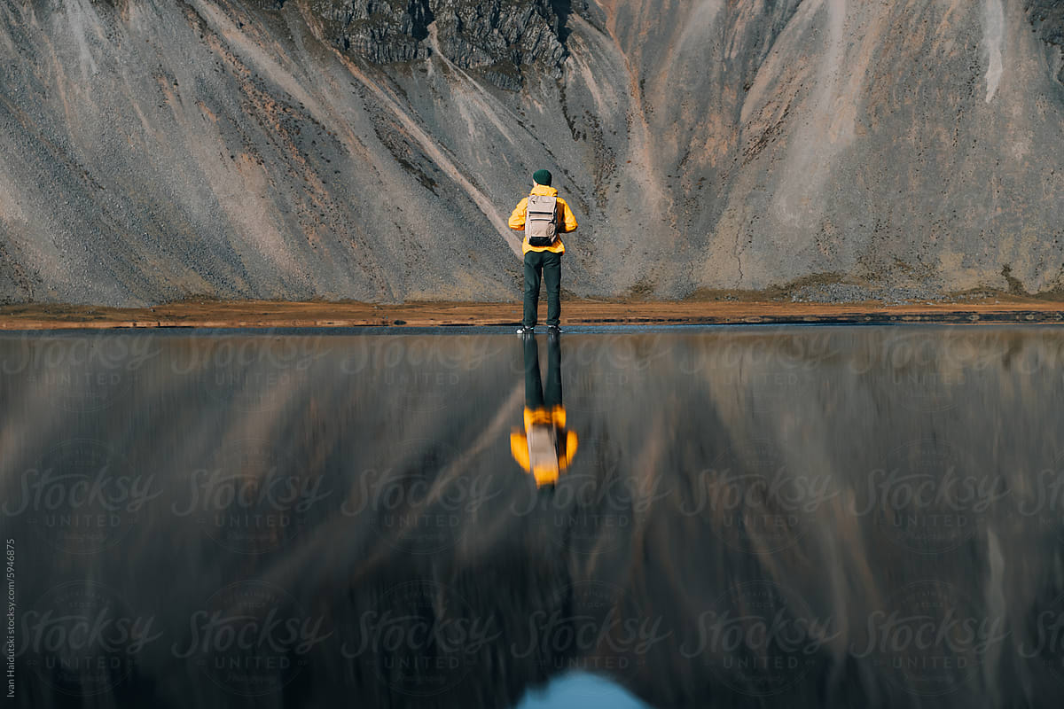 Man Reflection In Ocean Water. Mountain on Background.