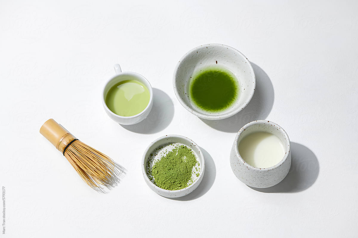 Matcha tea in a glass, bamboo matcha whisk, and bamboo whisk