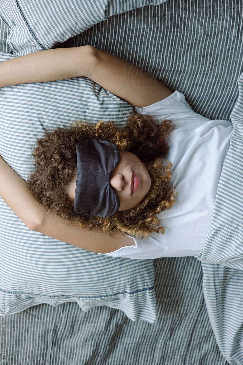 Portrait of a curly young woman in a sleep mask
