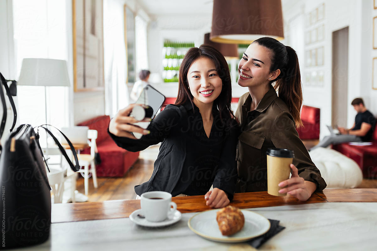 Multiracial friends taking selfie in coffeehouse