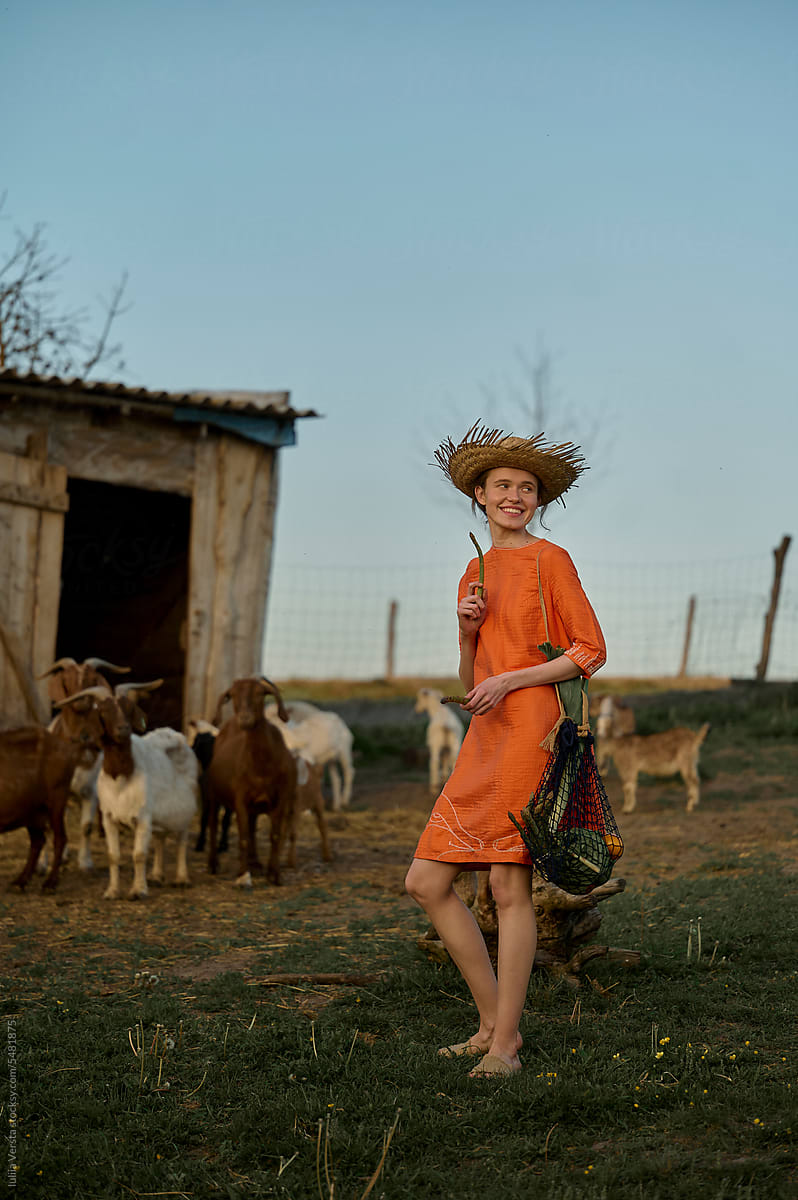 woman in a straw hat feeding goats