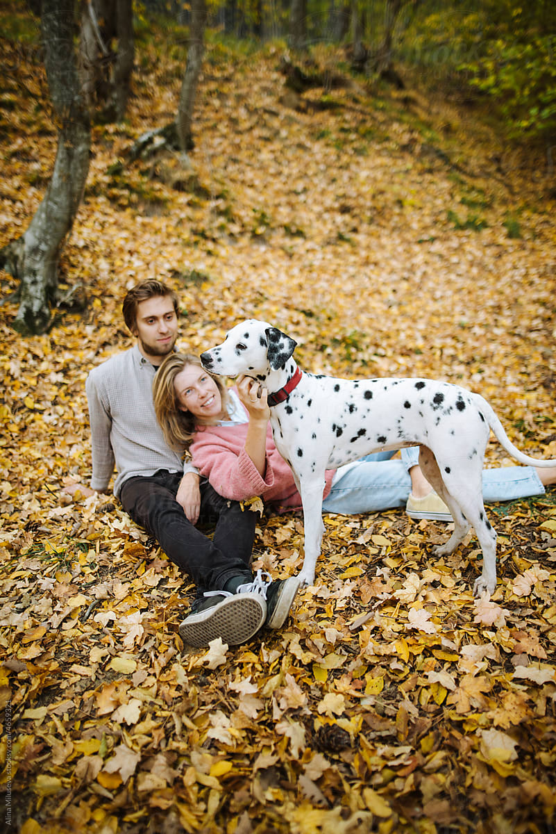 Happy loving couple with dog in fall season