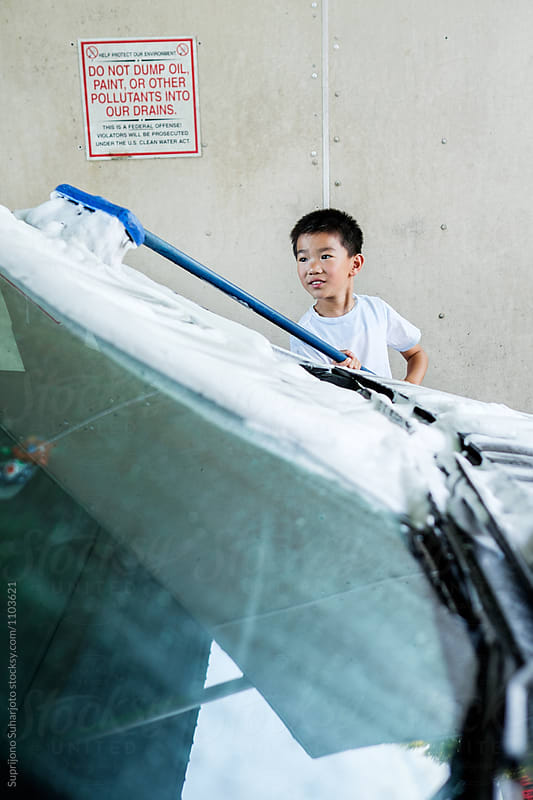 Asian kid washing a car at a car wash