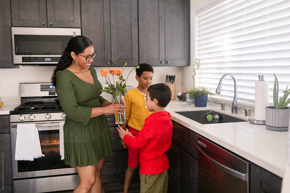 Boy giving flowers to mom in the kitchen