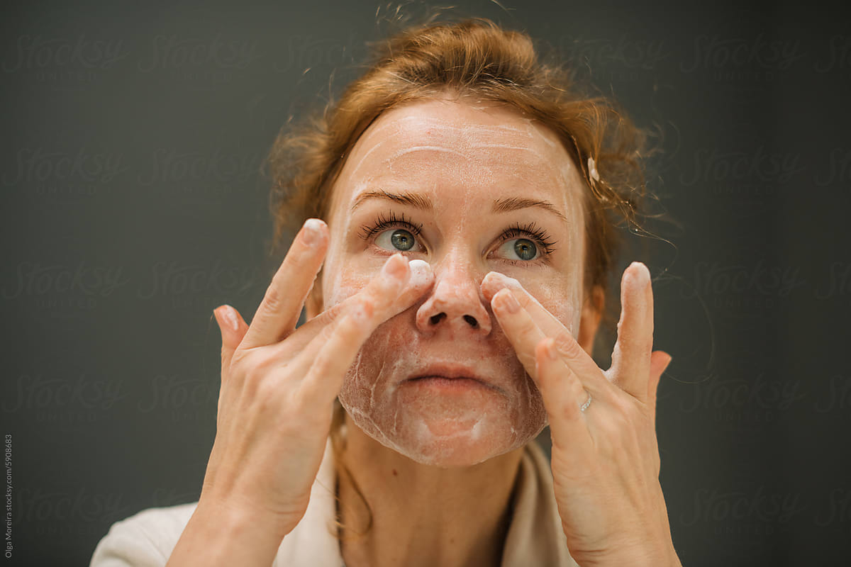 Woman cleansing her face with foaming soap