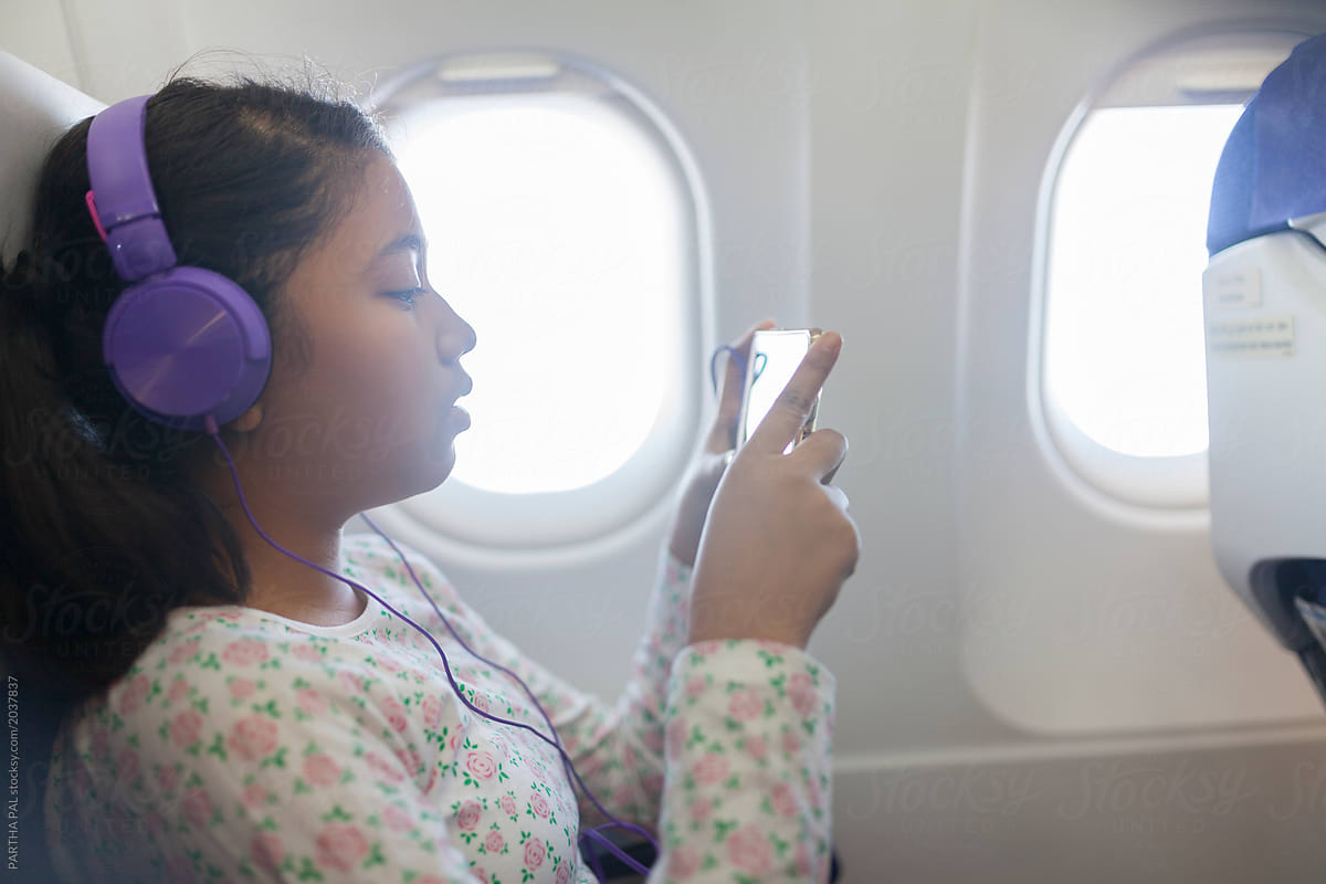 Teenage girl wearing headphone and enjoying song inside airplane