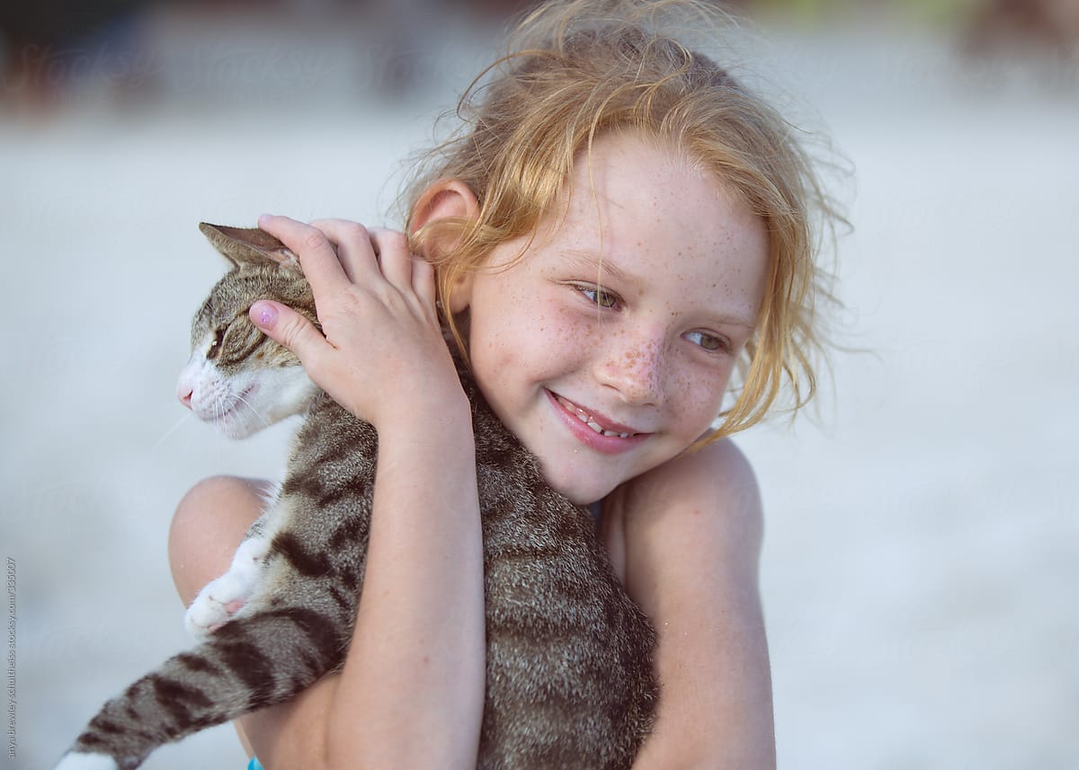 Young girl with blond hair holding a cat lovingly