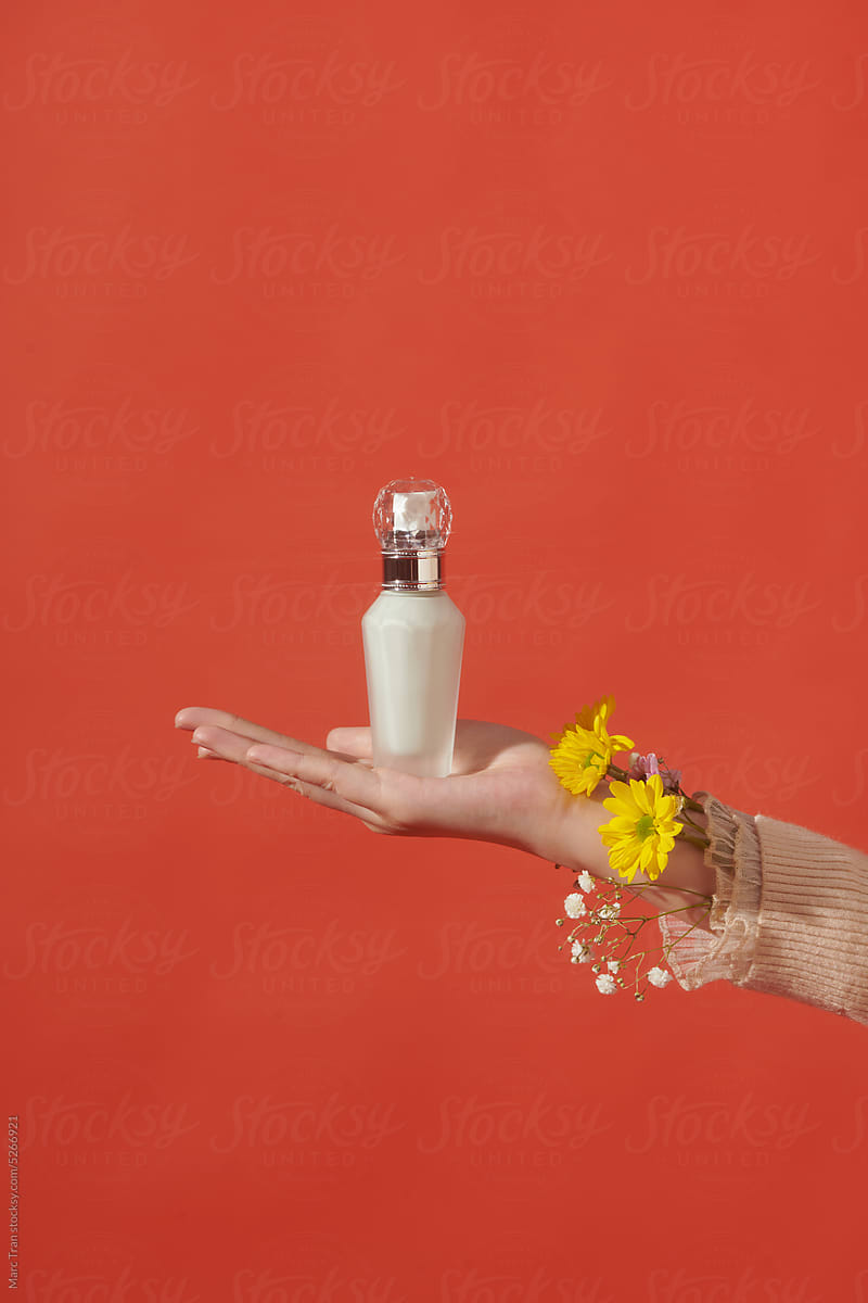 Female hands holding beauty bottles on red background