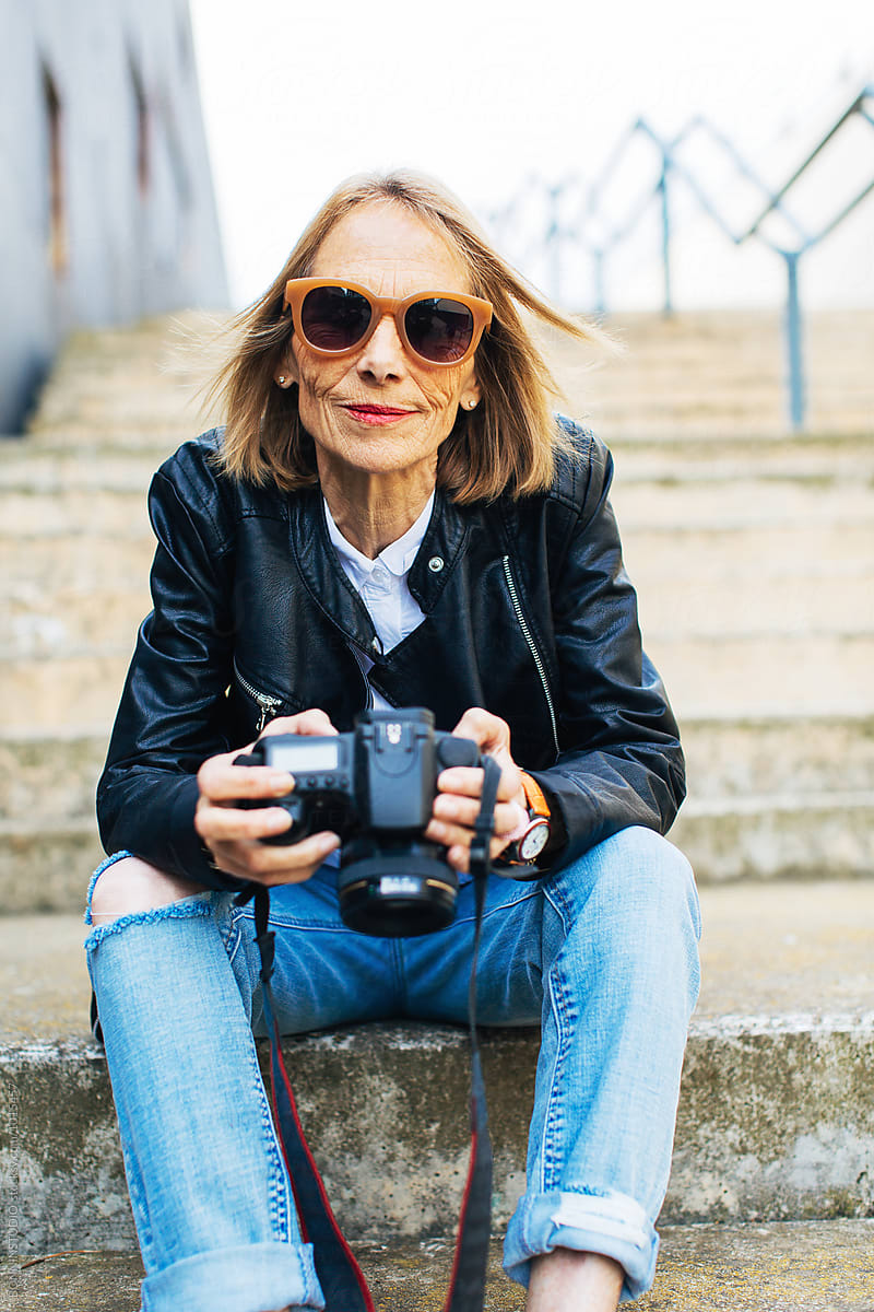 Portrait Of A Mature Woman Holding Her Camera Sitting On Stairs By