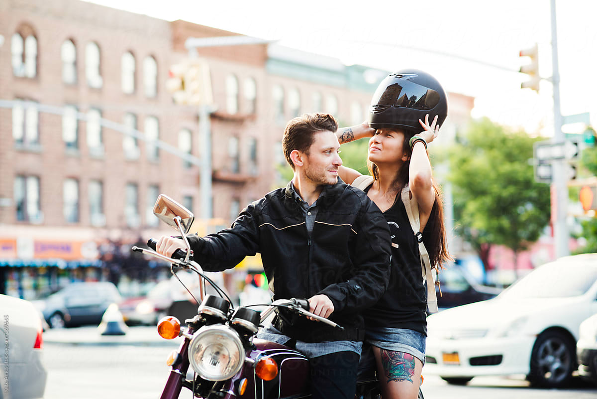 A young couple gets ready to ride a motorcycle in the city