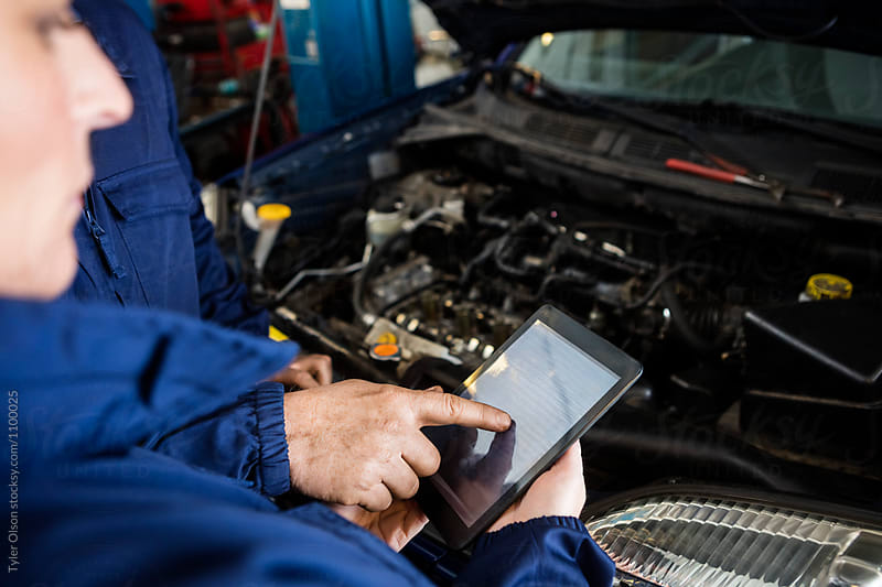 Mechanics Using Digital Tablet By Car In Garage