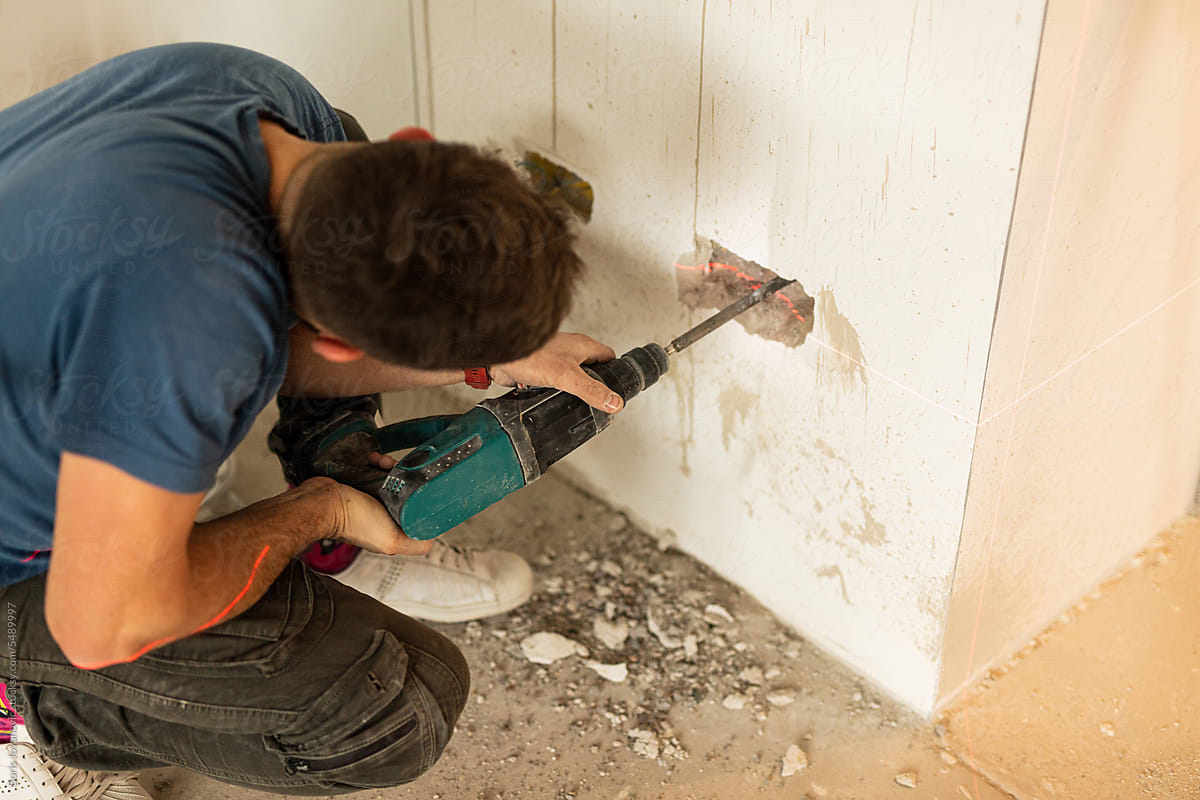 Electrician drills a hole in the wall for an electrical outlet