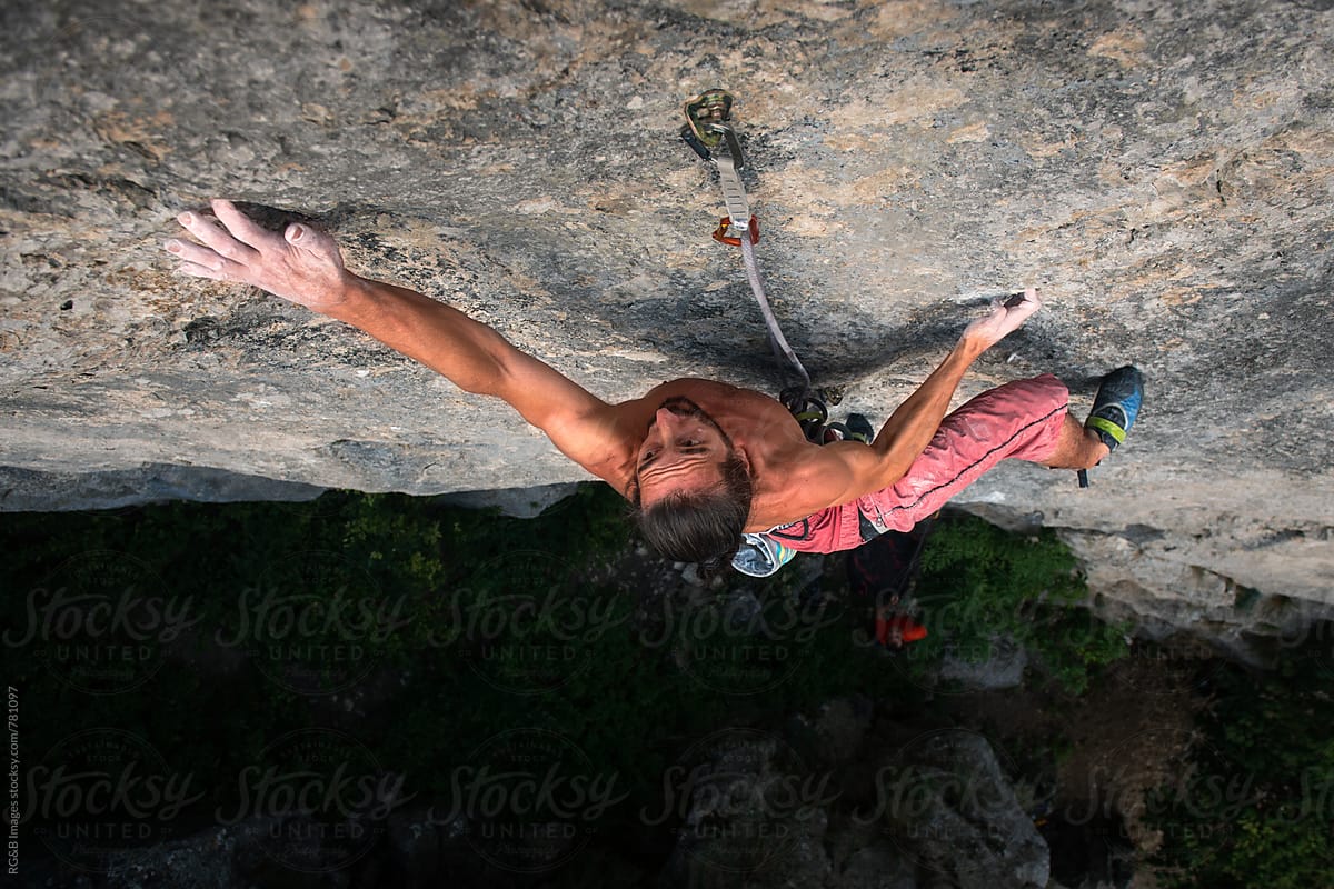 Rock climber on a steep rock face climbing a hard route